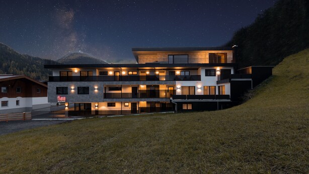 A modern multi-story hotel with a flat roof, large windows, and a well-lit facade. - Fliana Residenz (Ischgl)