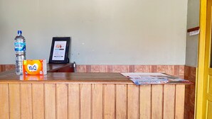 A wooden reception desk with a water bottle, a box of tissues, and a framed certificate. - Hotel O Guest House Leo Patra (Koealabadak)