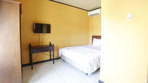 A room with a bed, a desk, a television mounted on the wall, and an air conditioning unit. - Hotel O Guest House Leo Patra (Koealabadak)