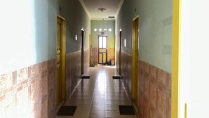A long, narrow hallway with tiled floors and walls, leading to a door at the end. - Hotel O Guest House Leo Patra (Koealabadak)