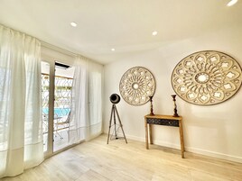 Een kamer met een groot raam, een statief en twee decoratieve borden aan de muur.