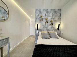 Een moderne slaapkamer met een bed, nachtkastjes en een spiegel aan de muur.