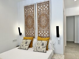 Een slaapkamer met een bed, twee decoratieve panelen en een nachtkastje.