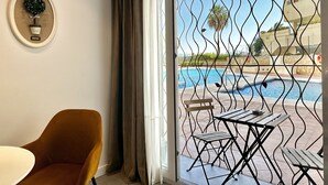 A room with a view of an outdoor swimming pool, a chair, a table, and a decorative wall piece. - Loft 18 Beach Front Marbella - EaW Homes (Marbella)