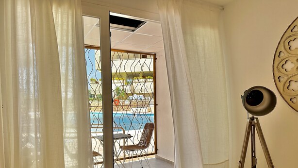 A room with a sliding glass door leading to an outdoor area with a pool, chairs, and a telescope. - Loft 18 Beach Front Marbella - EaW Homes (Marbella)