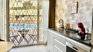 A modern kitchen with a view of a pool, a dining area with a table and chairs, and a red coffee machine. - Loft 18 Beach Front Marbella - EaW Homes (Marbella)