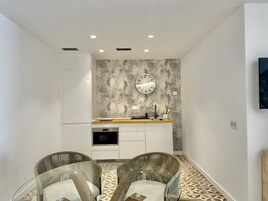 Een moderne keuken met een ingebouwde oven, een houten aanrecht en een klok aan de muur.