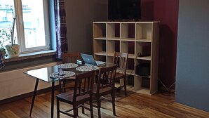 A dining area with a table, chairs, a laptop, a television on a stand, and a bookshelf. - Apartament Promenada (Rzeszów)