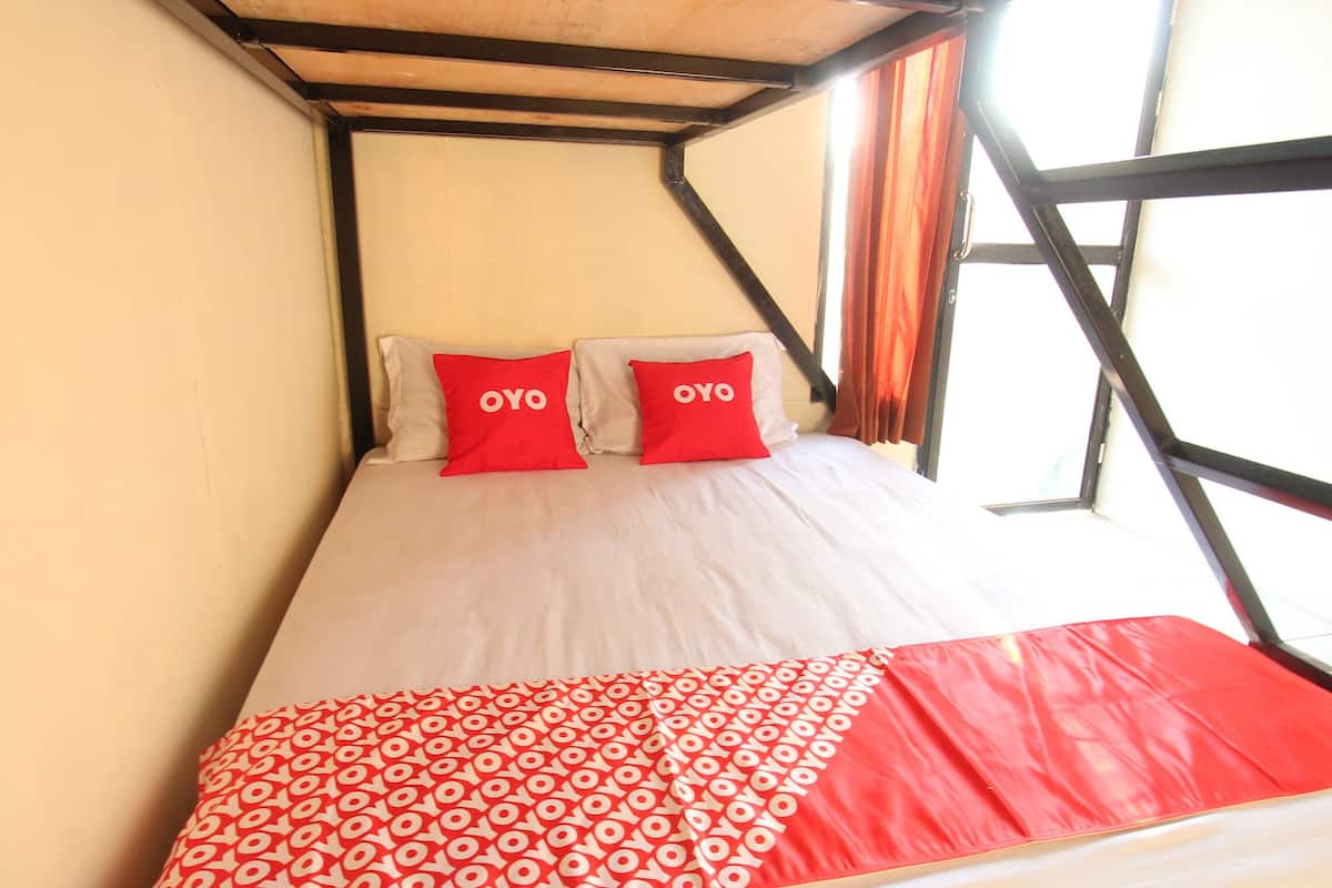 A bunk bed with two red pillows labeled "OYO" and a red and white patterned blanket.