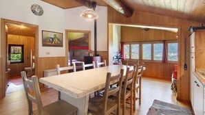 Un interior de madera con una mesa de comedor, sillas, un reloj y un cuadro.