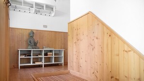 Una habitación con suelo de madera, un estante blanco, una estatua y una escalera de madera.