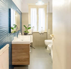 Une salle de bain moderne avec un meuble-lavabo en bois, deux vasques, des toilettes et une fenêtre avec des rideaux.