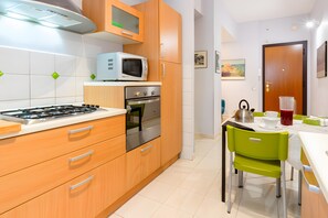 Une cuisine moderne avec des meubles en bois, une cuisinière à gaz, un four et un four à micro-ondes.
