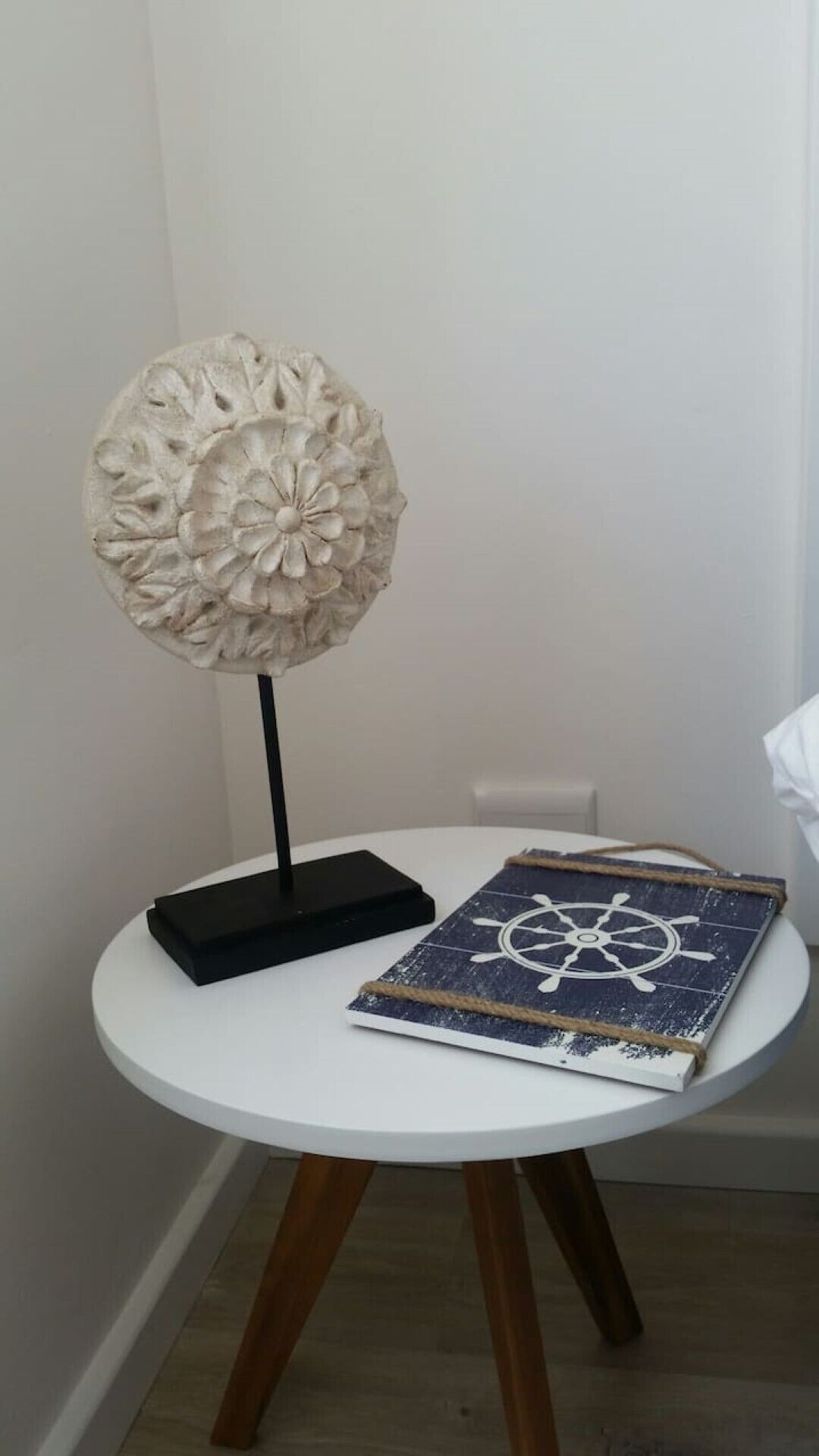 A white table with a decorative object and a book with a nautical wheel design.