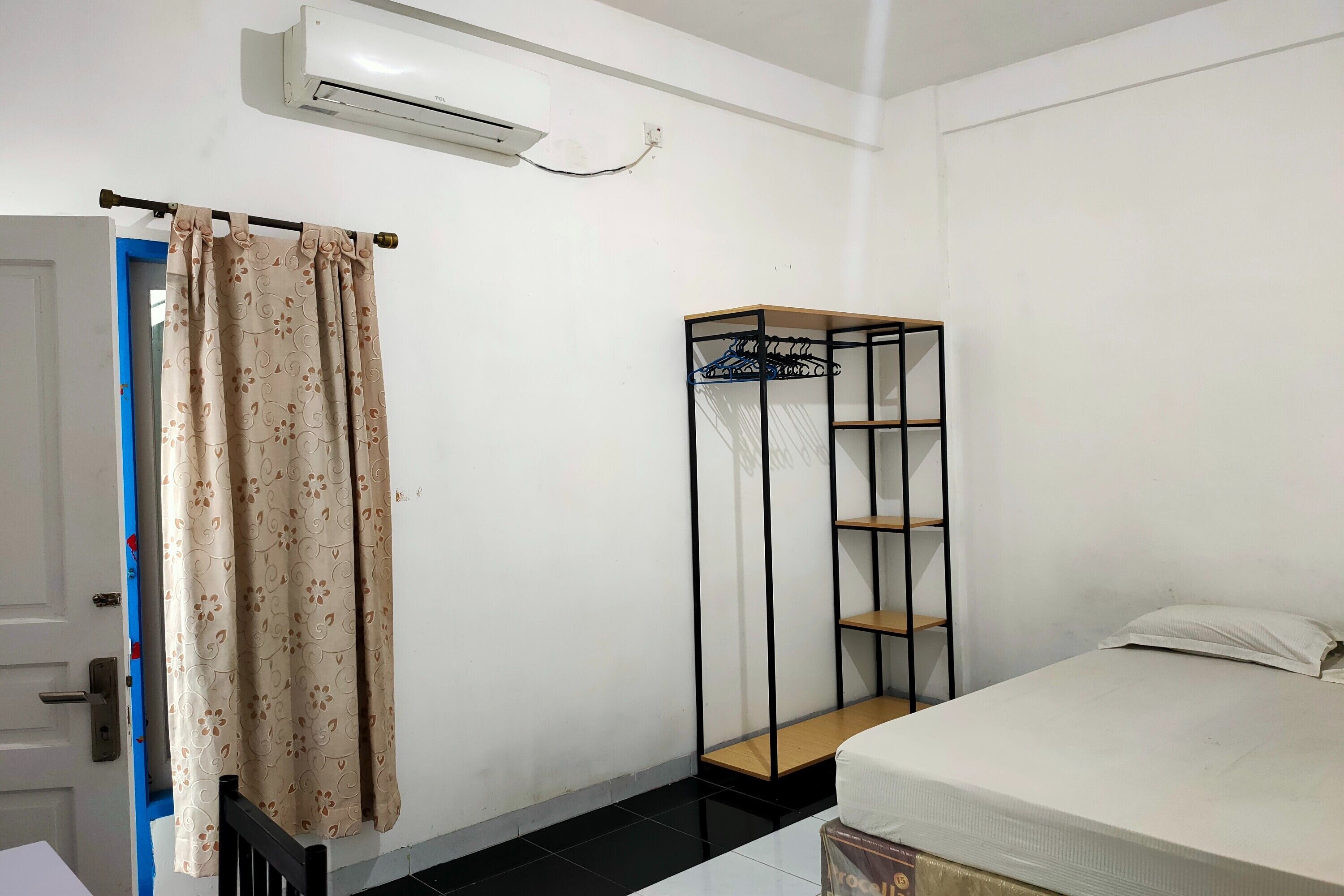 A bedroom with a bed, a wardrobe, and an air conditioning unit.