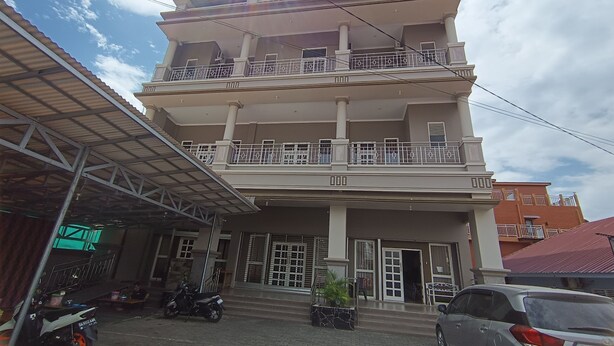 A multi-story building with a covered entrance and a staircase leading to the main entrance. - Hotel O Pondok Puti Sartika SyariahNearPasar Jum'at Aluh Aluh (Banjarmasin)
