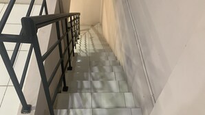 A staircase with a metal railing, tiled steps, and a plain wall. - Hotel O Pondok Puti Sartika SyariahNearPasar Jum'at Aluh Aluh (Banjarmasin)