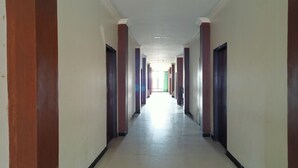 A long, narrow hallway with alternating red and blue columns, leading to a bright exit. - Hotel O Pondok Puti Sartika SyariahNearPasar Jum'at Aluh Aluh (Banjarmasin)