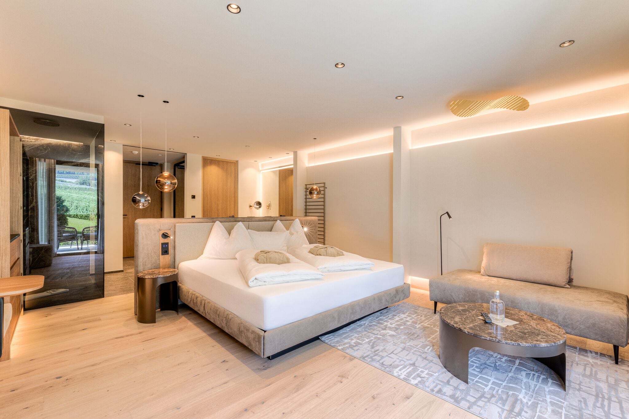 Un dormitorio moderno con una cama grande, un sofá, una mesita de centro y vistas a un jardín.