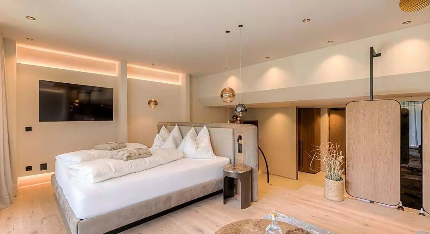 A modern bedroom with a large bed, bedside tables, a TV, and a wooden cabinet.