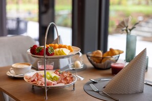 Une table mise pour le petit-déjeuner, avec un plateau à trois niveaux, une tasse de café, des croissants et une serviette.