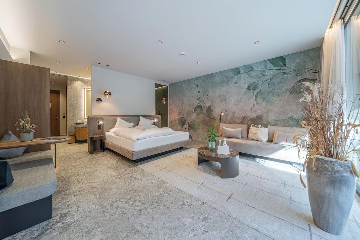 Quarto moderno com cama, sofá e uma janela grande.