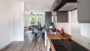 A modern kitchen with a wooden countertop, stainless steel appliances, and a dining area with a table and chairs. - Spacious 3 Bed Apartment in Waterloo, Liverpool (Liverpool)