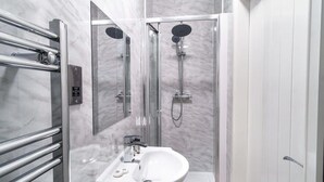 A modern bathroom with a glass-enclosed shower, a white sink, and a marble-tiled wall. - Spacious 3 Bed Apartment in Waterloo, Liverpool (Liverpool)