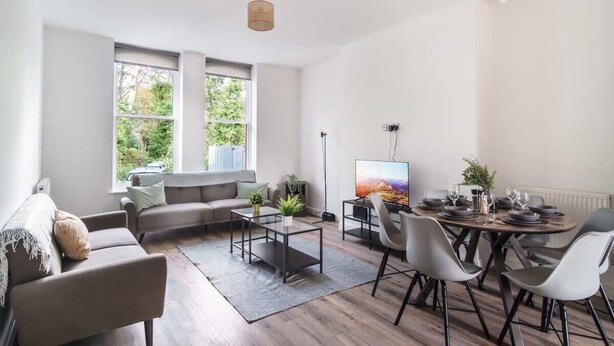 A modern living room with a sofa, coffee table, and dining area. - Spacious 3 Bed Apartment in Waterloo, Liverpool (Liverpool)