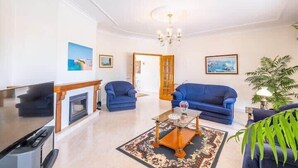 Una sala de estar con chimenea, dos sofás azules, una mesa de centro y un televisor.