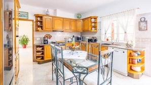 Una cocina con armarios de madera, una mesa de comedor con sillas, un microondas y un fregadero.