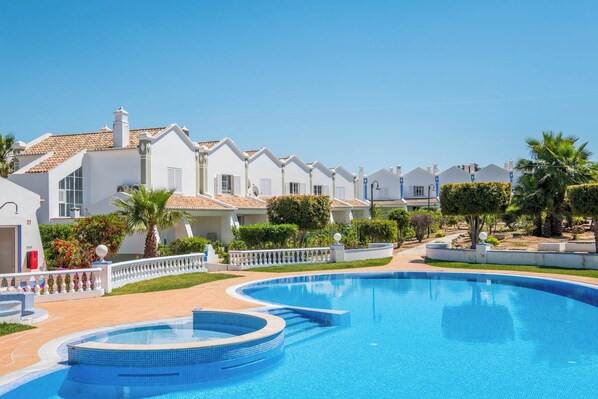 Relax by the serene pool surrounded by lush greenery and palm trees.