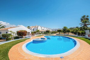 Una piscina rodeada por una valla blanca, con un cielo azul despejado.