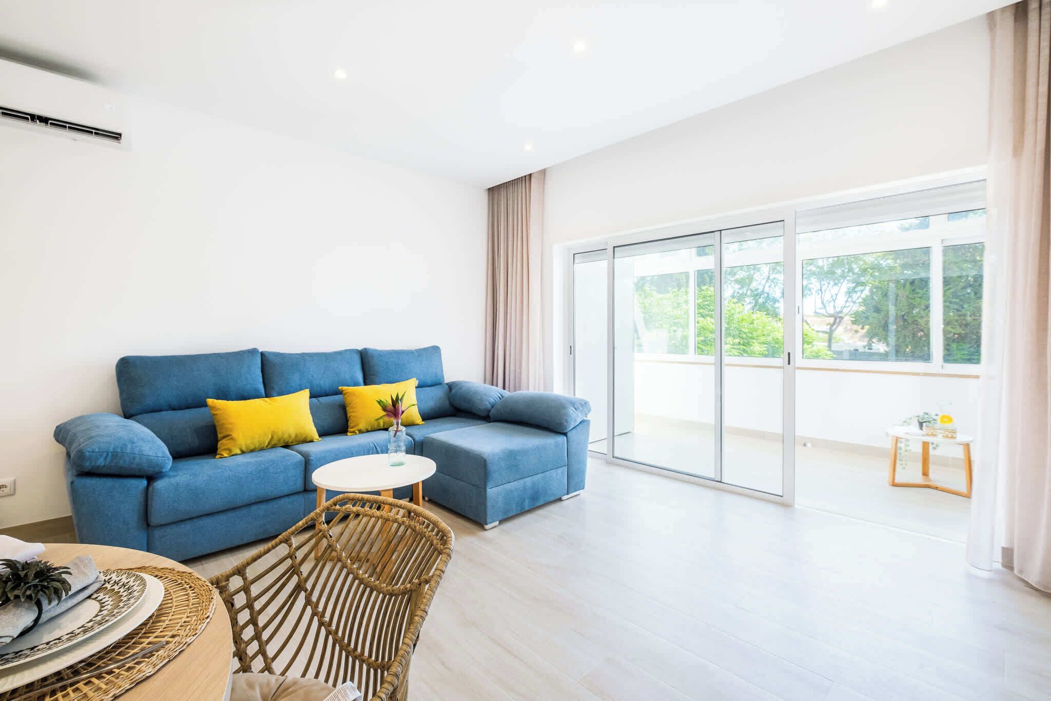 A modern living room with a blue sofa, a small round table, and a wicker chair.