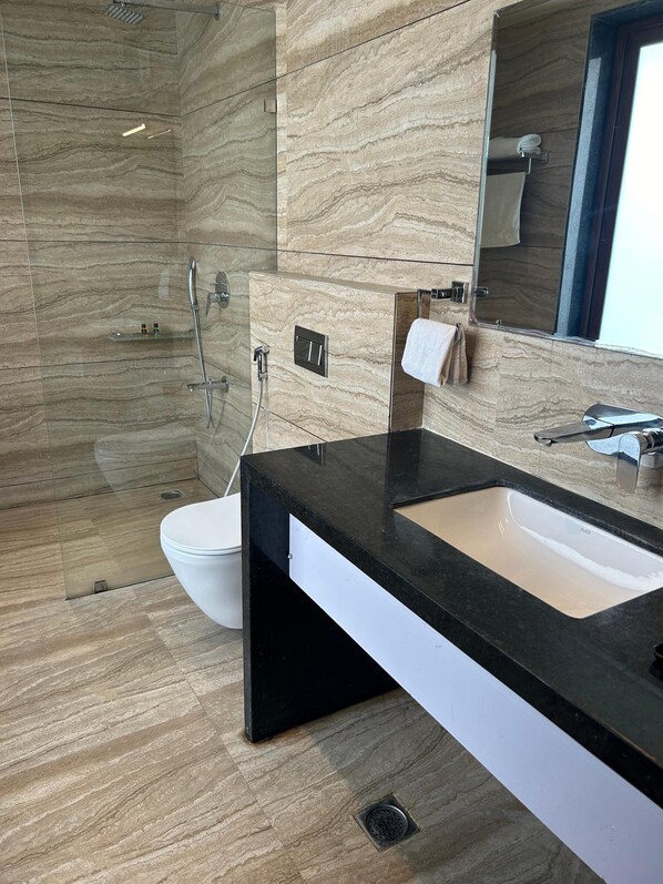 A modern bathroom with a black sink, a toilet, and a shower area.
