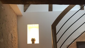 Una escalera de madera con barandilla metálica, que lleva a un rellano con un pequeño ventanal.