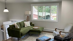 A living room with a sectional sofa, a black leather chair, a small ottoman, a lamp, and a window with a view of the outside. - Beautifully updated home in the South Hills (Missoula)