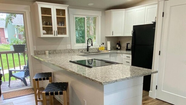 A kitchen with white cabinets, a granite countertop, and a black refrigerator. - Beautifully updated home in the South Hills (Missoula)