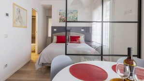 A modern bedroom with a bed, a table with a bottle and glasses, and a large window. - Delightful apartment in Ponte Milvio district (Roma)