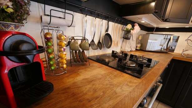 Een moderne keuken met een houten aanrecht, een rode apparatuur en diverse keukengerei aan de wand.