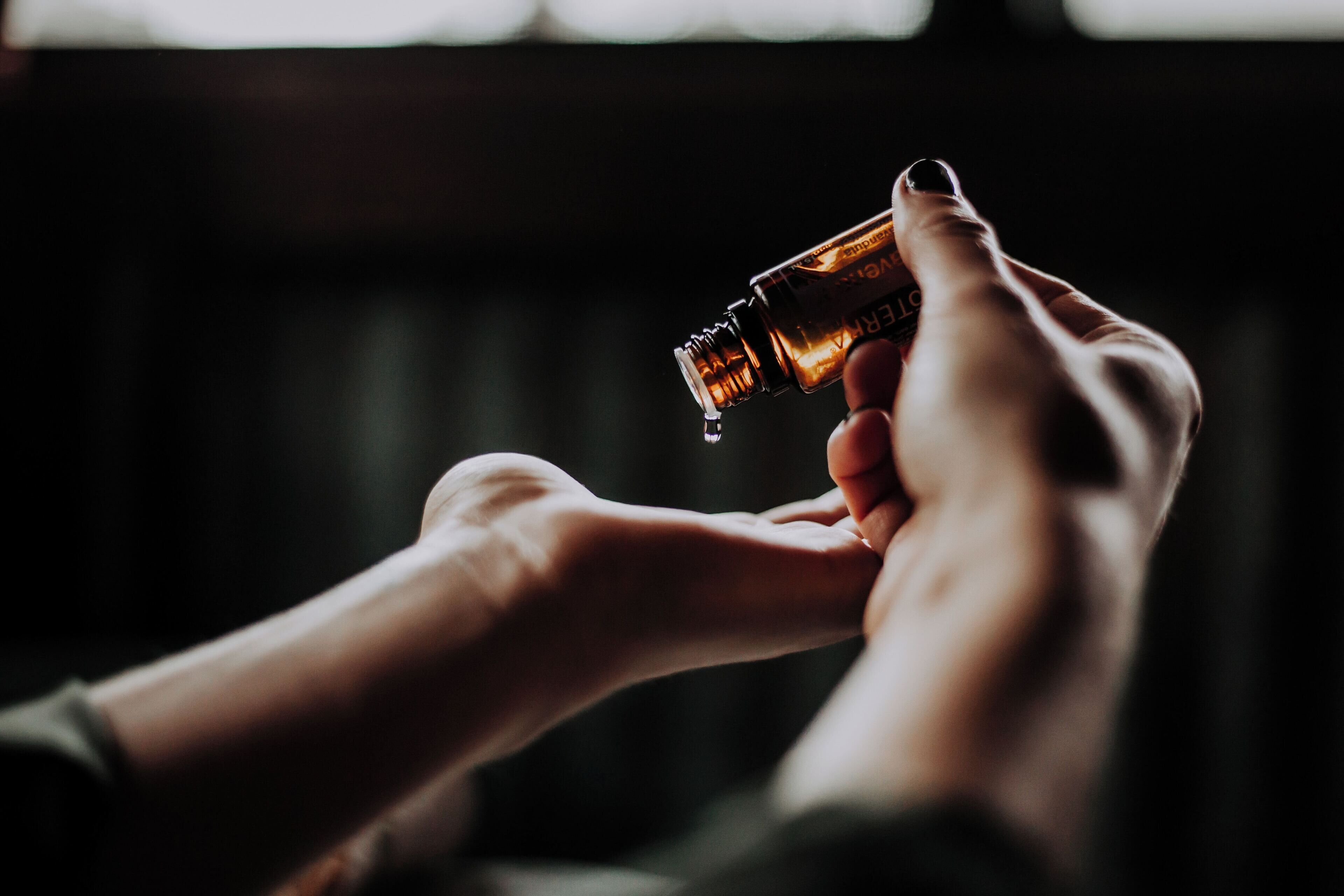 A person holding a small bottle with a dropper, likely containing a liquid.