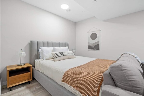 A modern bedroom with a bed, bedside table, and a wall-mounted artwork.