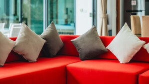 Una sala moderna con un sofá rojo, una mesa de centro de cristal y vistas a un balcón a través de amplias ventanas.