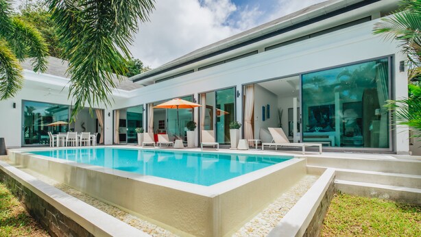Una casa moderna con piscina, puertas de vidrio amplias y mobiliario de exterior.