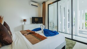 Habitación de hotel moderna con una cama grande, un televisor de pantalla plana, una mesita de noche con lámpara y un ventanal con vistas al exterior.