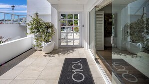 A modern entrance with a glass door, potted plants, and a doormat with the name 'YOLO'.