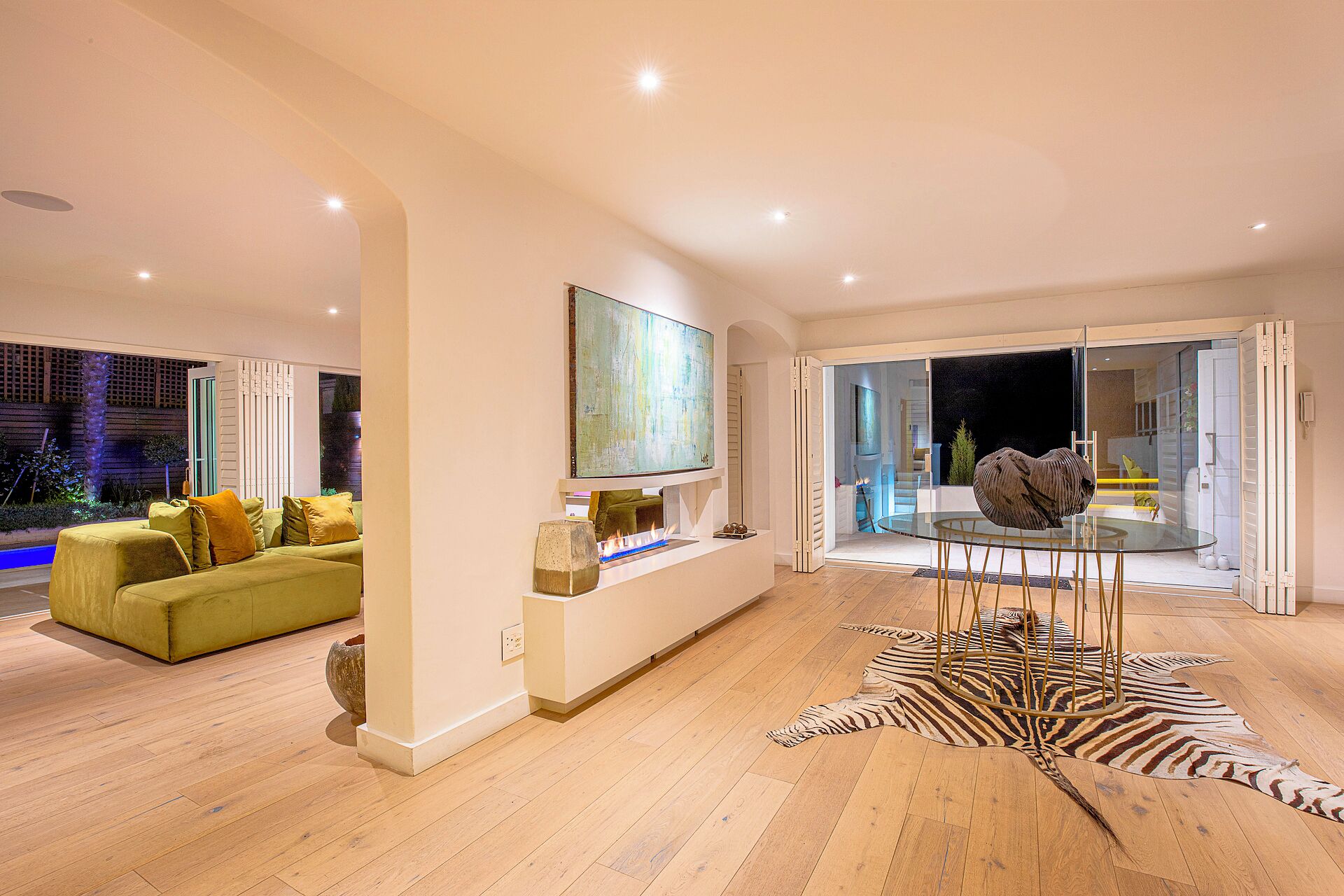 Un salon moderne avec un canapé vert, une table basse en verre et un tapis à motifs zébrés.
