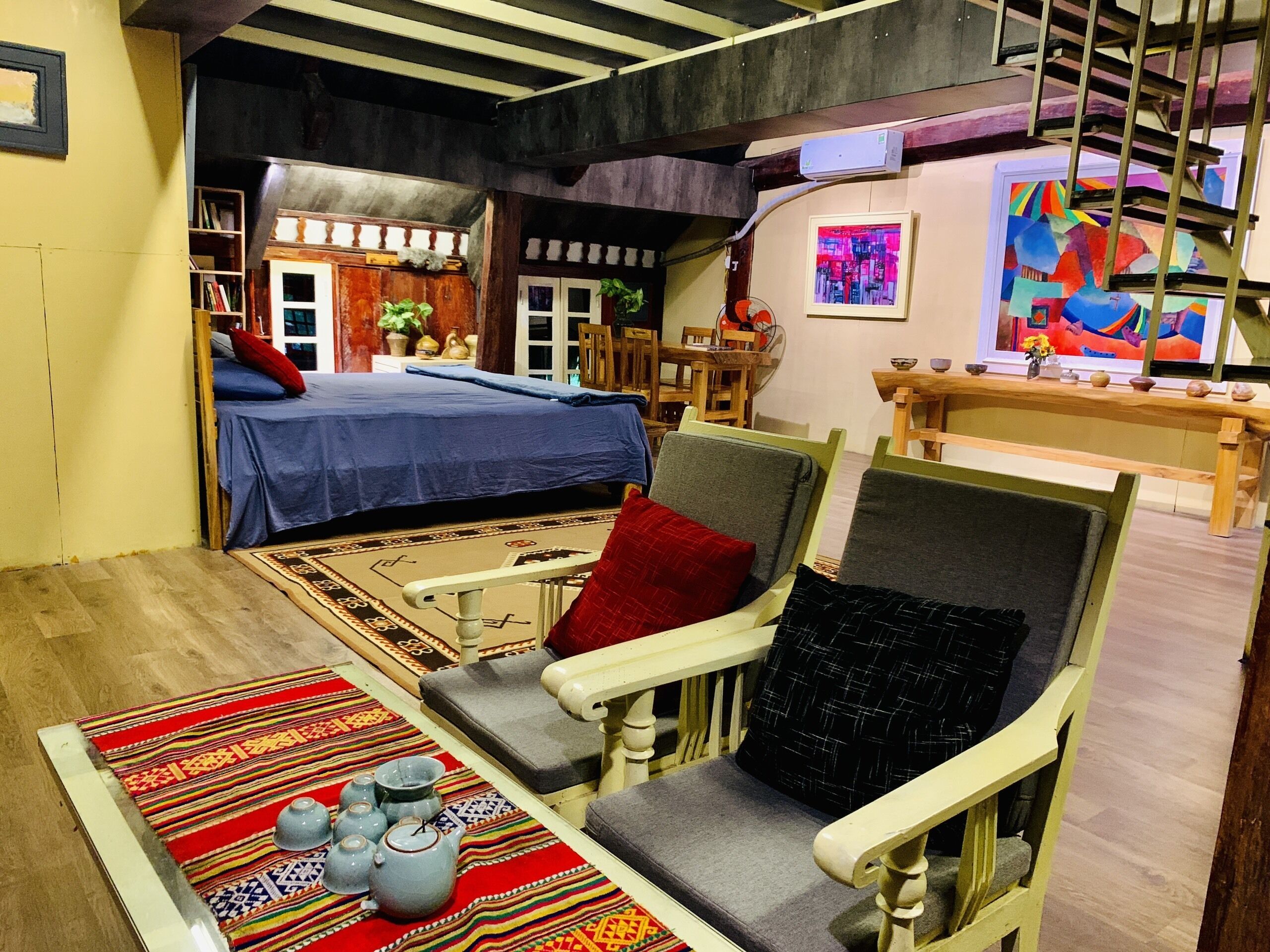 A cozy room with a bed, a dining table with chairs, a sofa, and a small kitchen area.