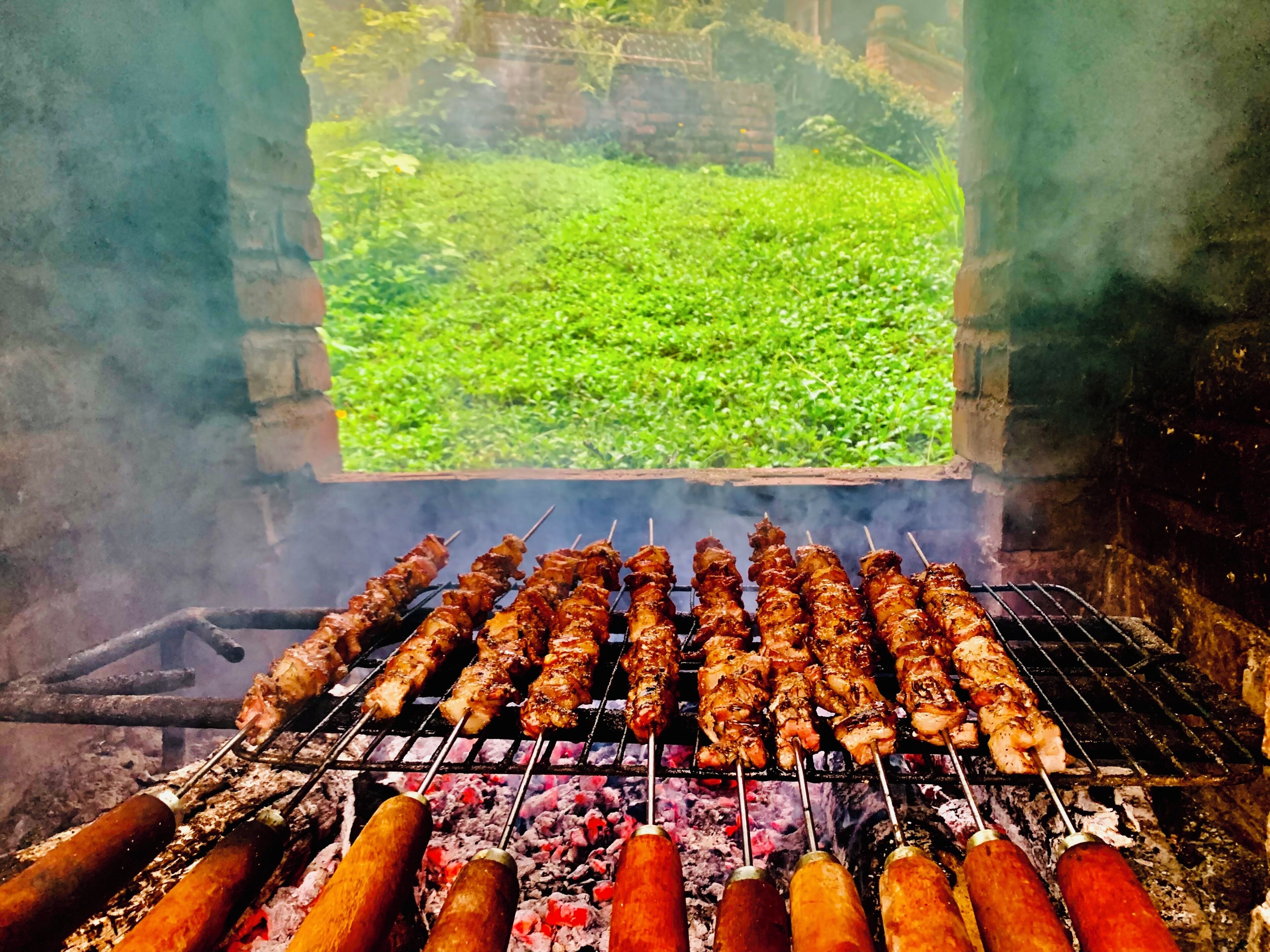 A grill with skewers of meat and sausages being cooked.