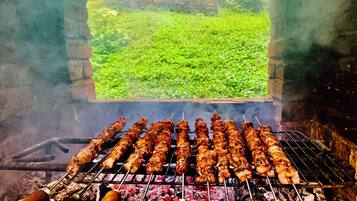 A grill with skewers of meat and sausages being cooked.
